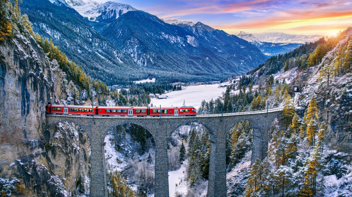 Red train crossing a winter mountain viaduct